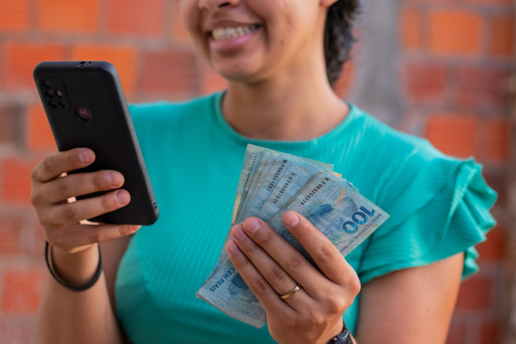 Mulher meia idade com celular na mão ganhando dinheiro.